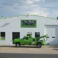 Green tow truck parked in front of a white building with