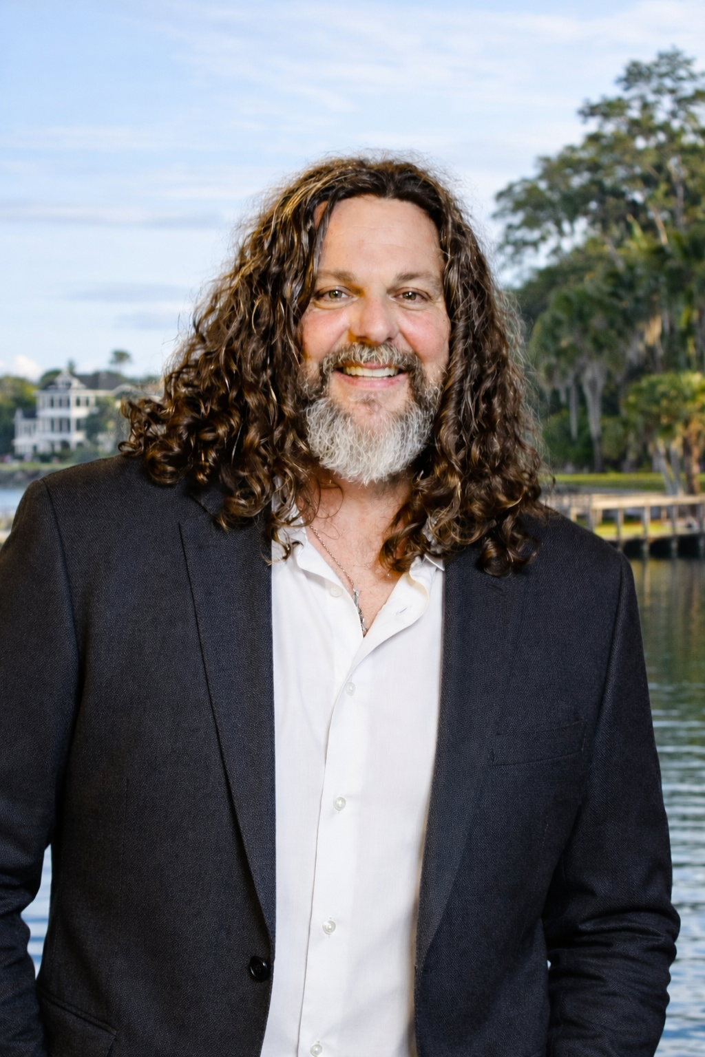 A woman is sitting at a desk with a laptop and a vase of flowers.