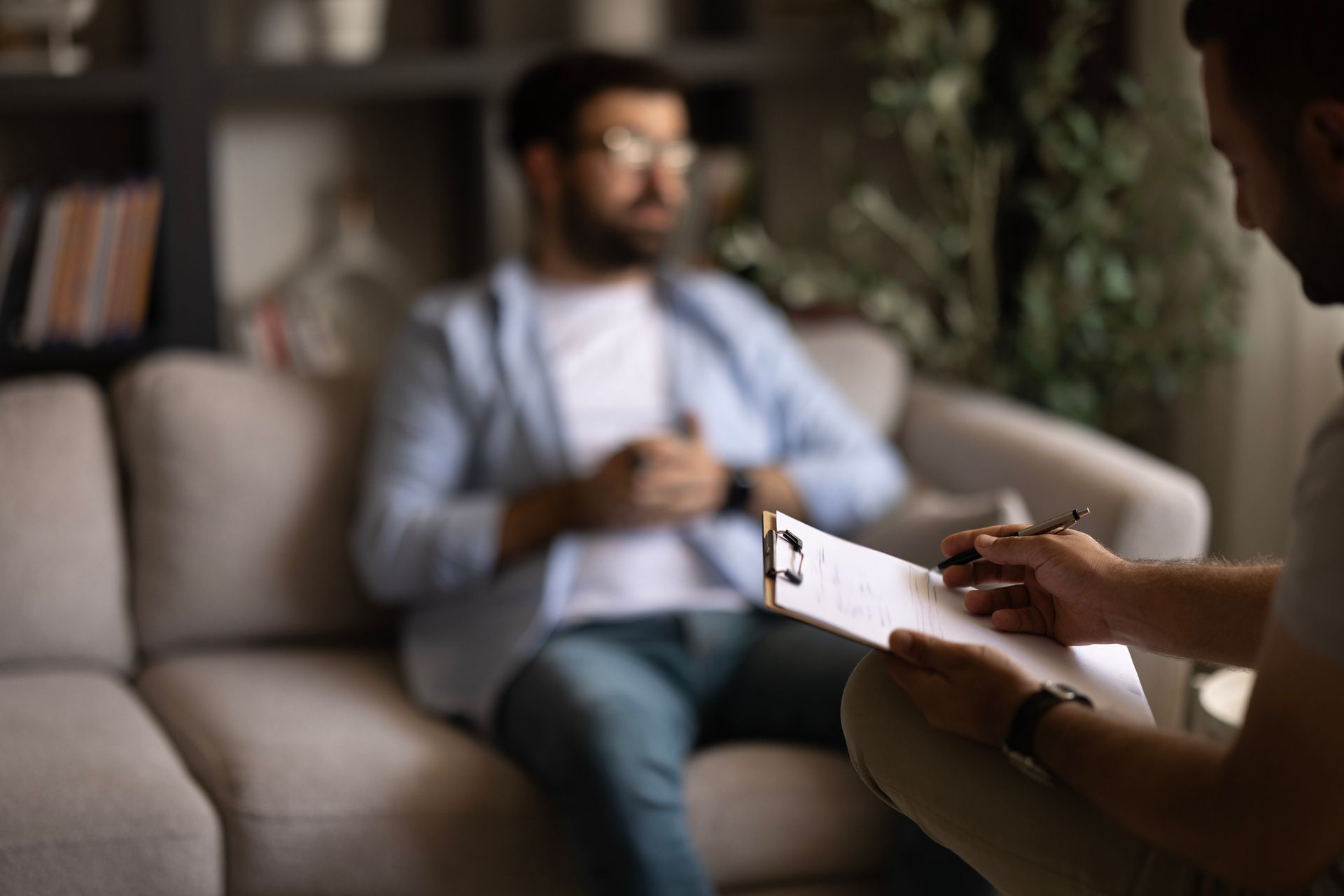 A psychologist talks with a patient and takes notes during a professional therapy session. A psychologist talks with a patient and takes notes during a professional therapy session.