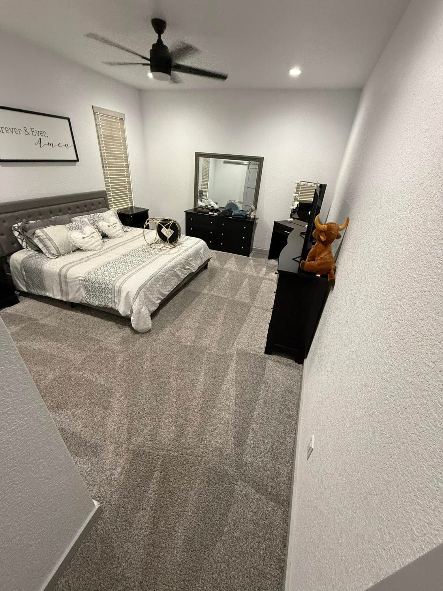 A bedroom with a bed , dresser , mirror and ceiling fan.