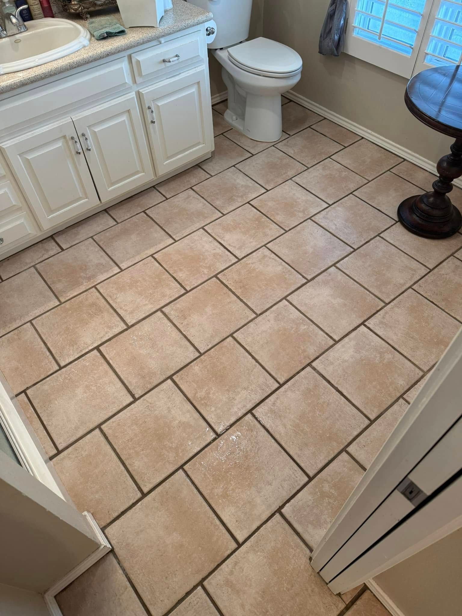 A bathroom with a toilet , sink , and tile floor.