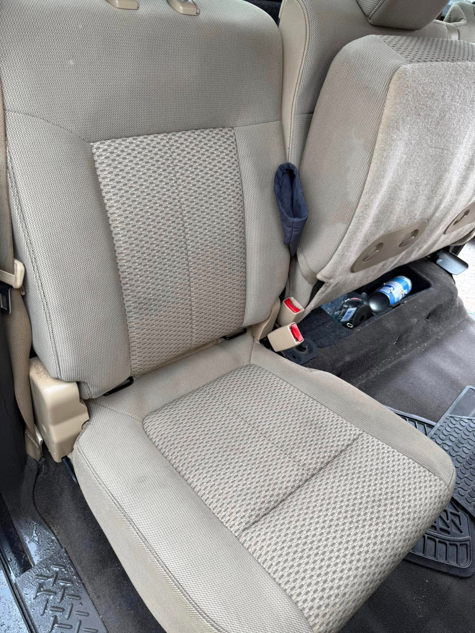 The back seat of a car with a seat belt on it.