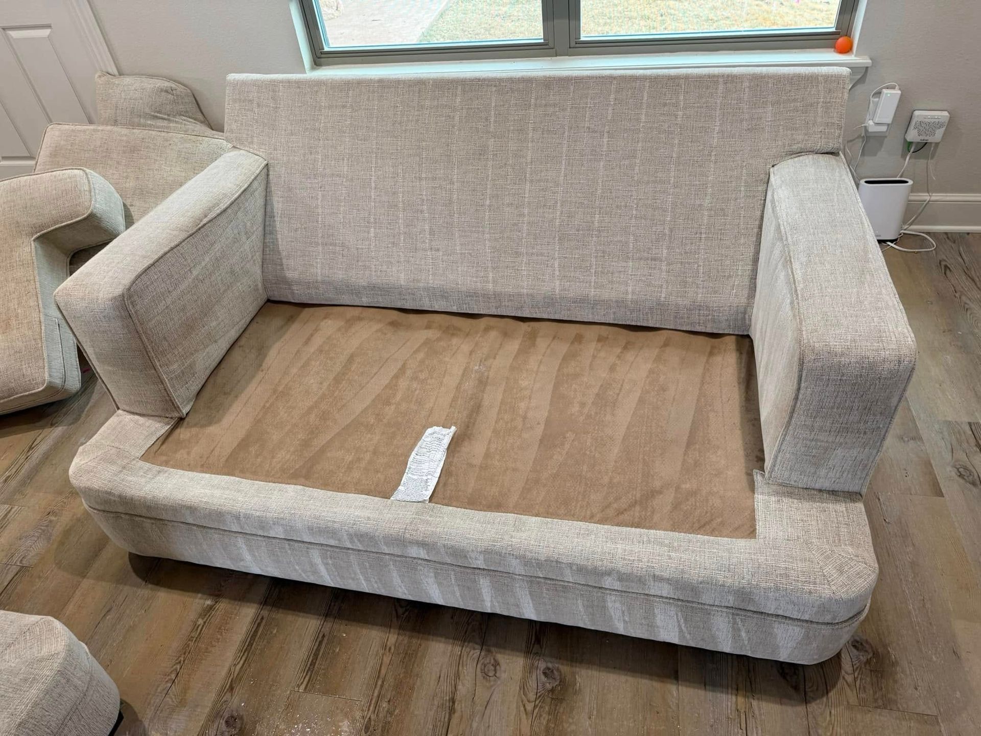 A white couch is sitting on a wooden floor next to a window.