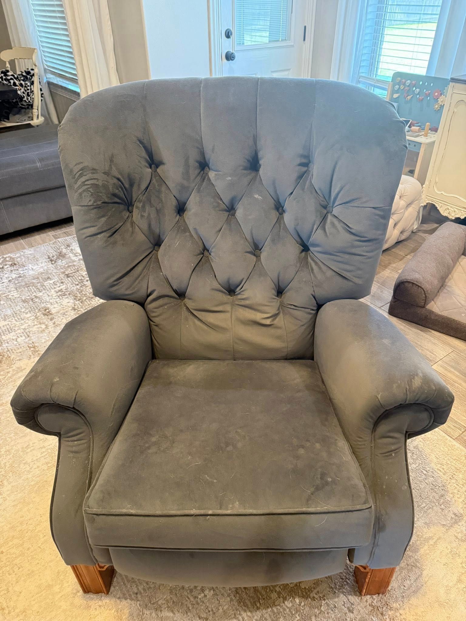 A grey chair is sitting on a carpet in a living room.
