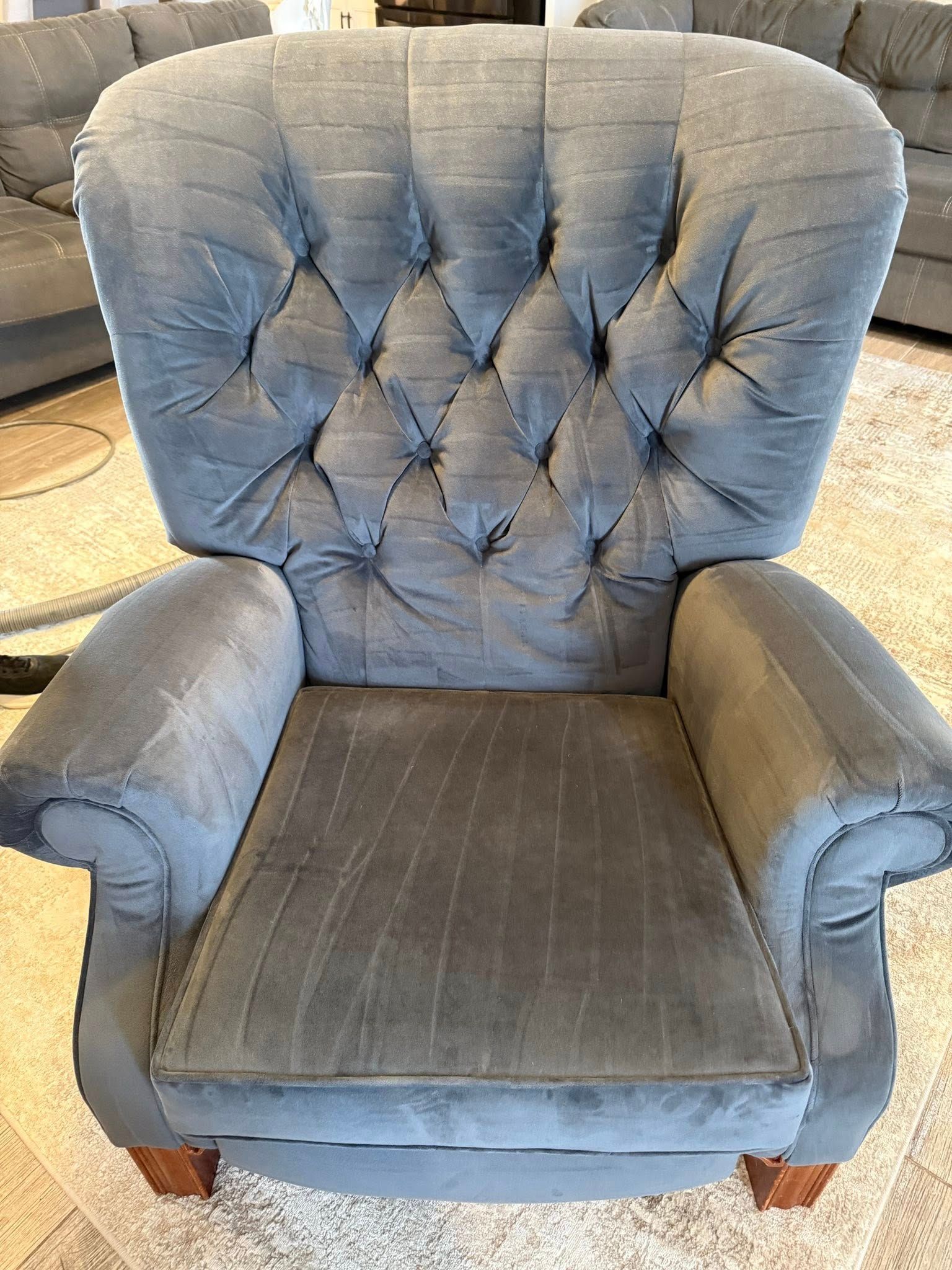 A grey chair is sitting in a living room next to a couch.