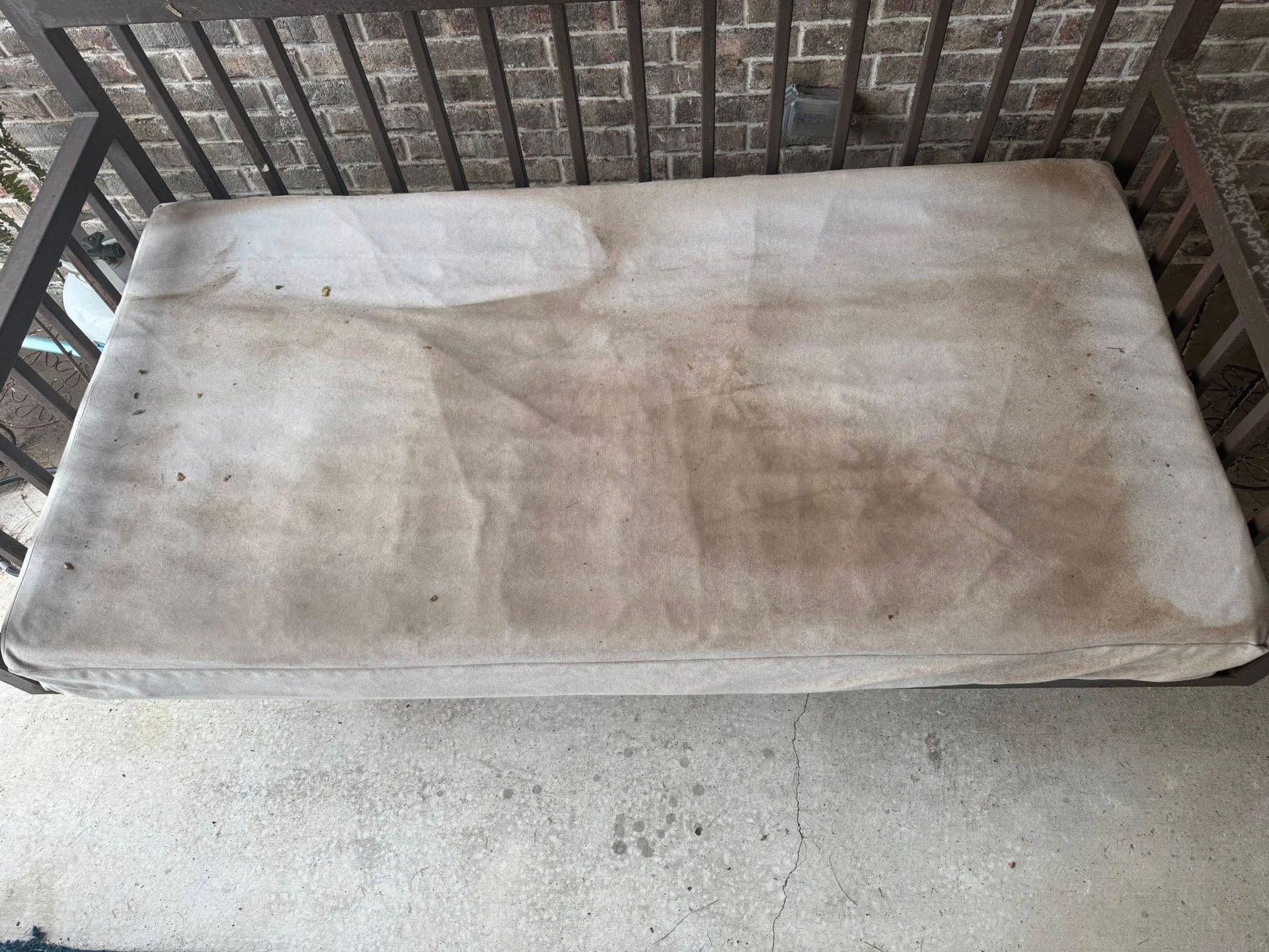 A dirty mattress is sitting on a balcony next to a railing.