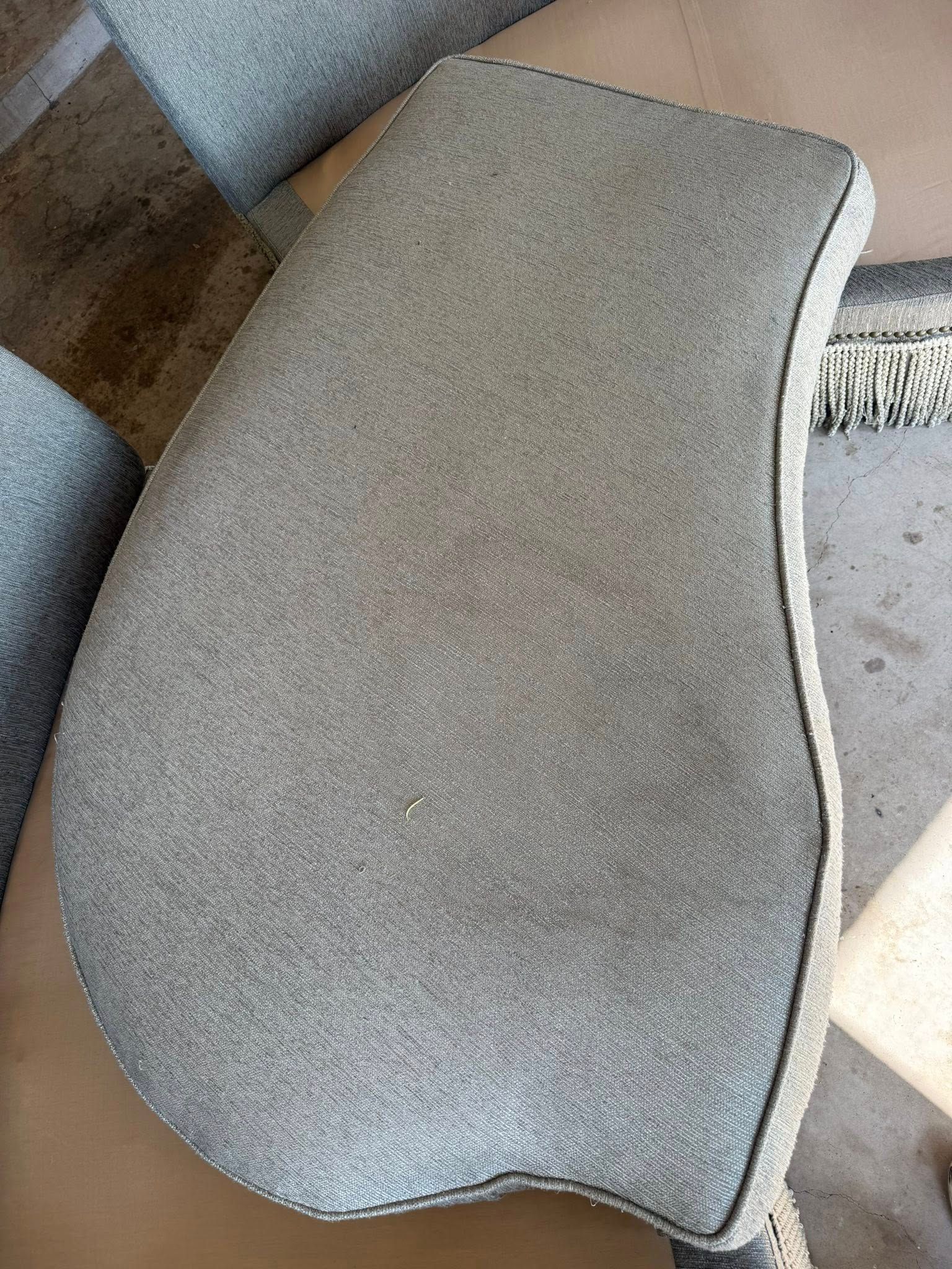 A close up of a gray pillow on a couch.