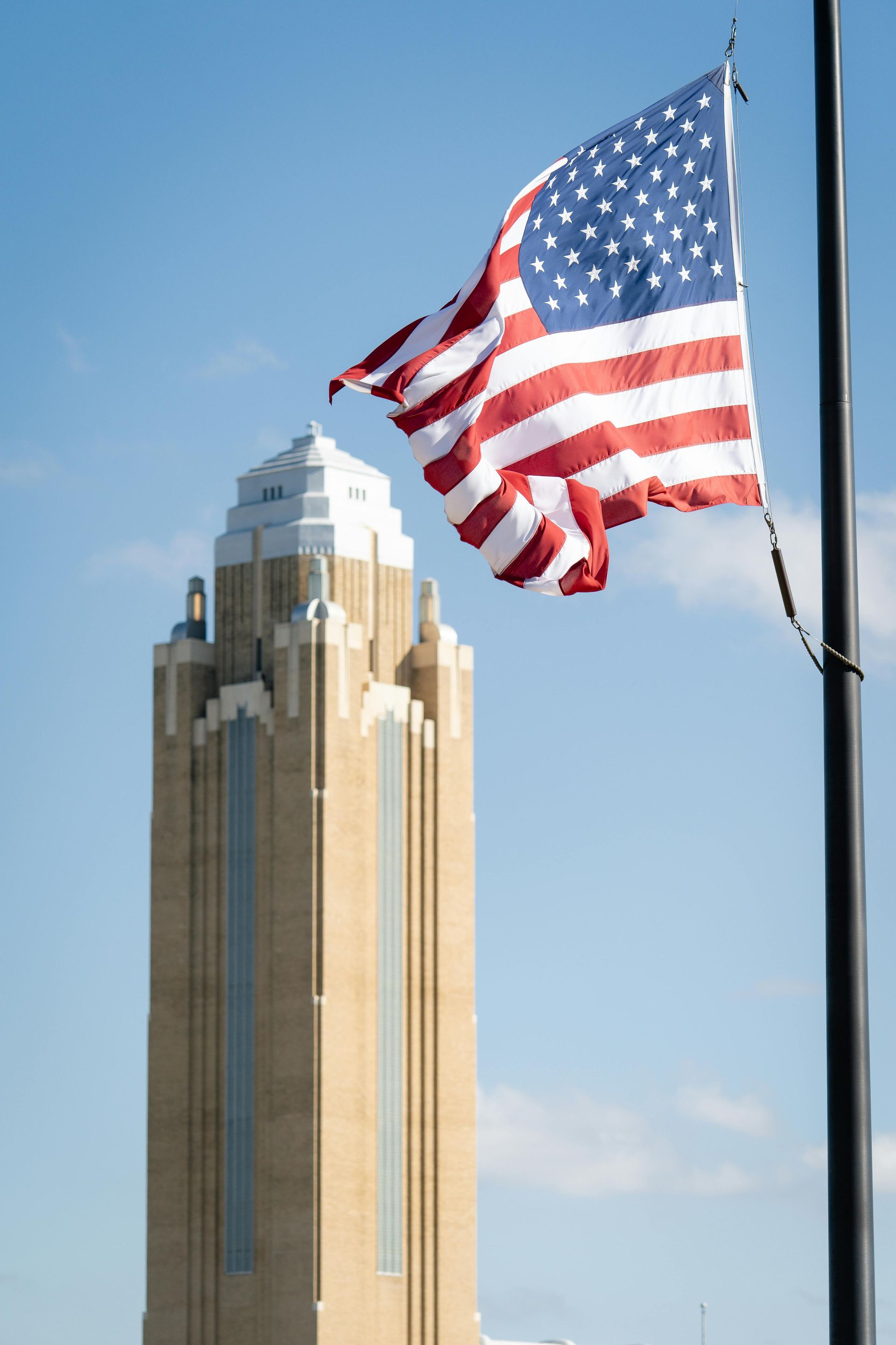 An american flag is flying in front of a tall building