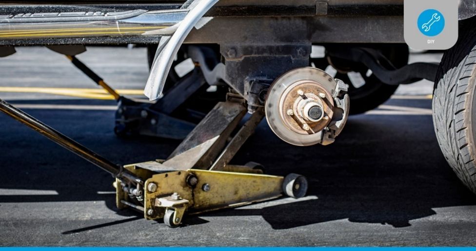 A car is being lifted by a jack on the side of the road.