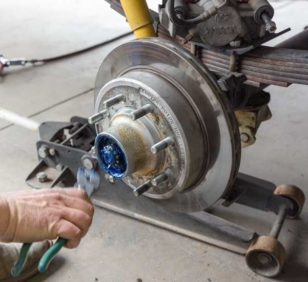 A person is working on a brake disc with a pair of pliers