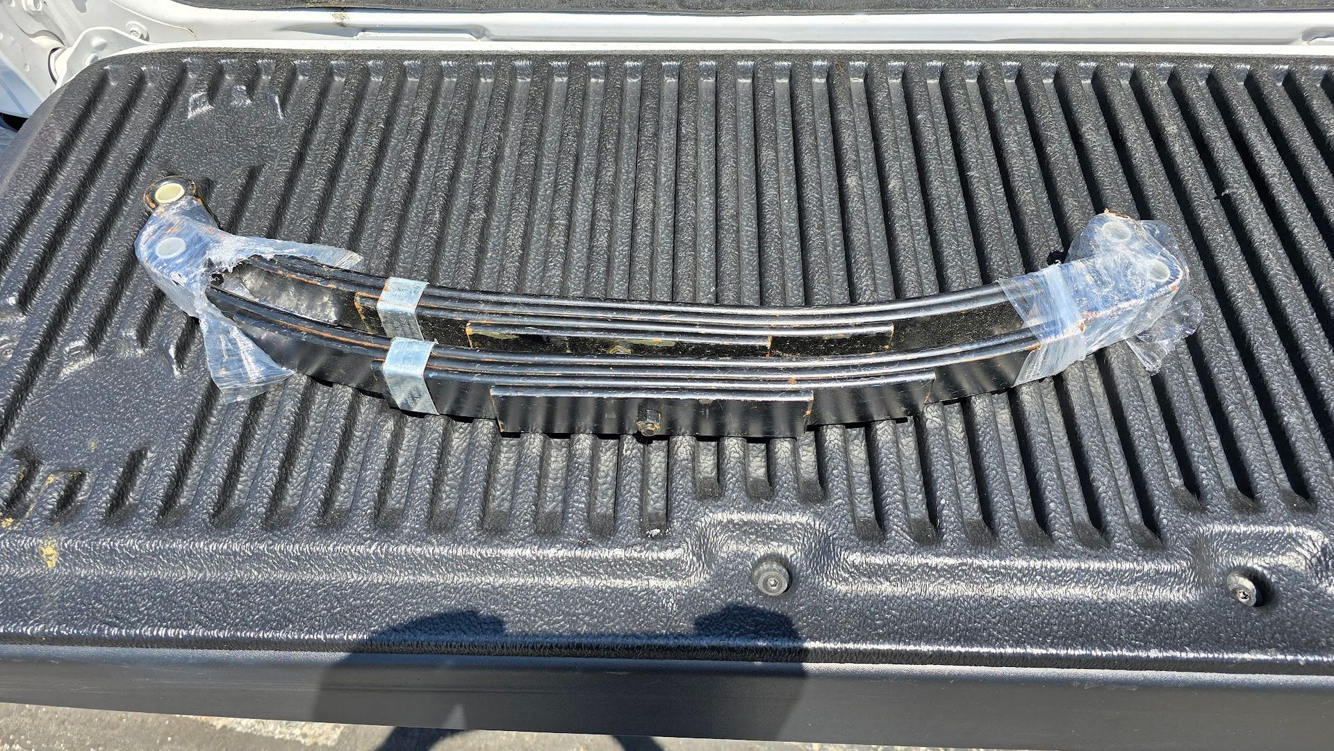 A leaf spring is sitting on top of a truck bed.