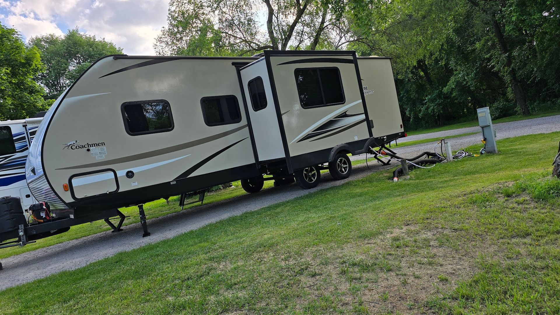 A rv is parked on the side of a road in a grassy area.