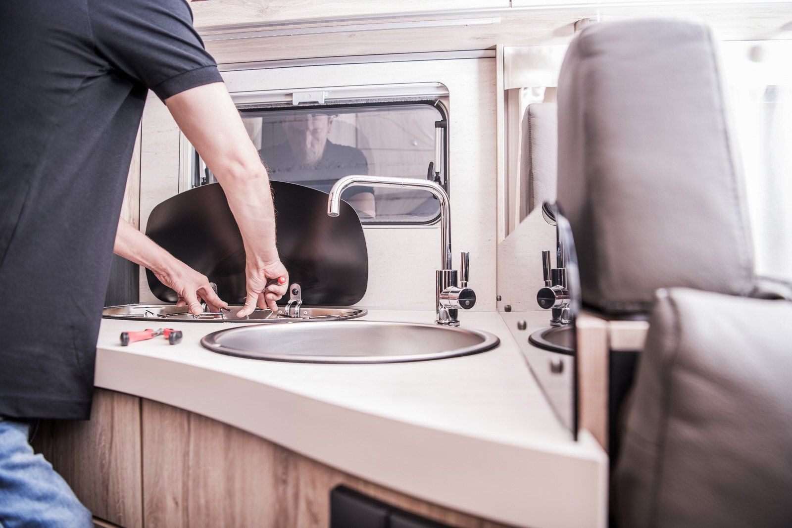 A person wearing red gloves is working on a boiler.