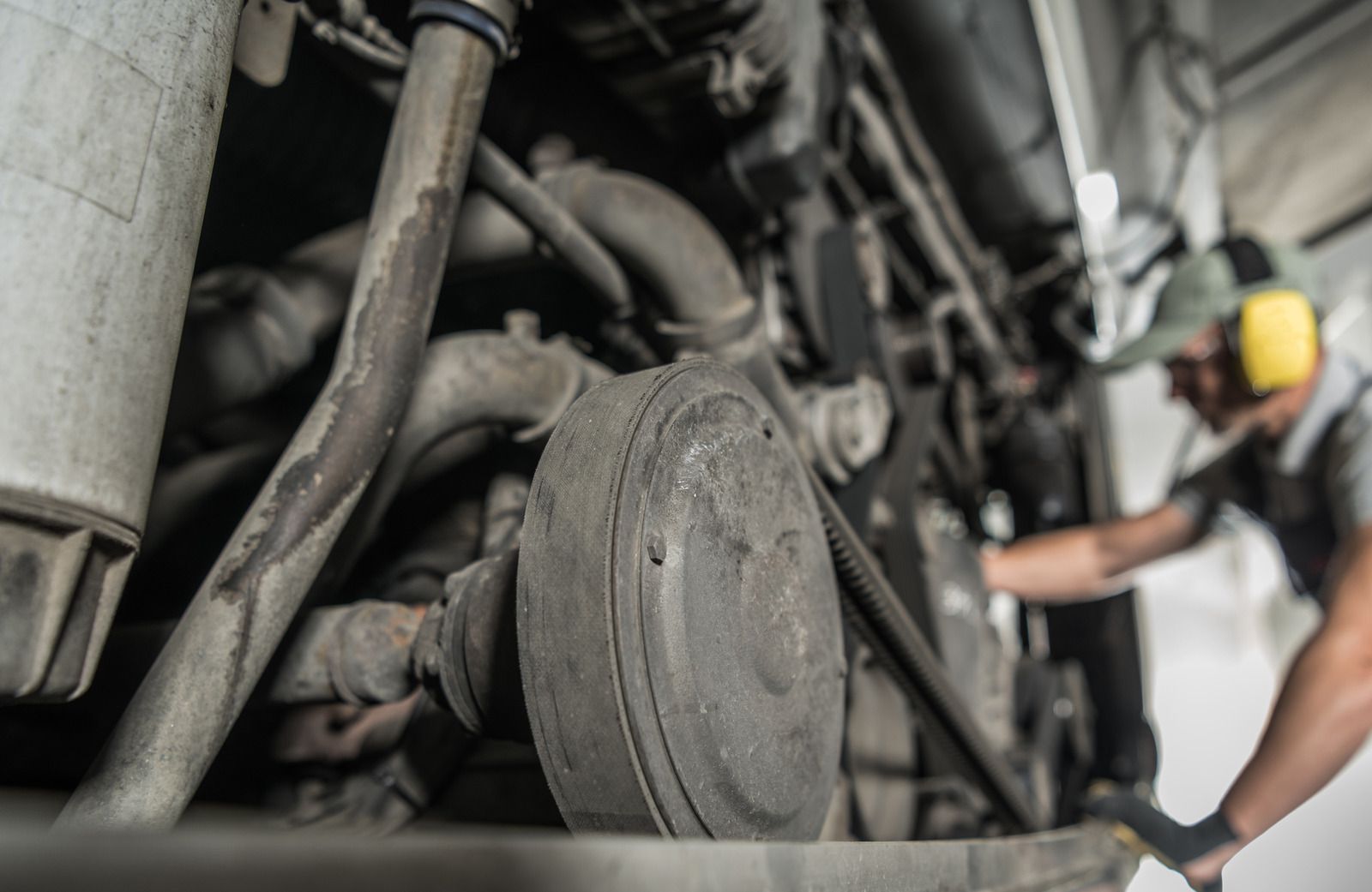 A man is working on the engine of a truck in a garage.