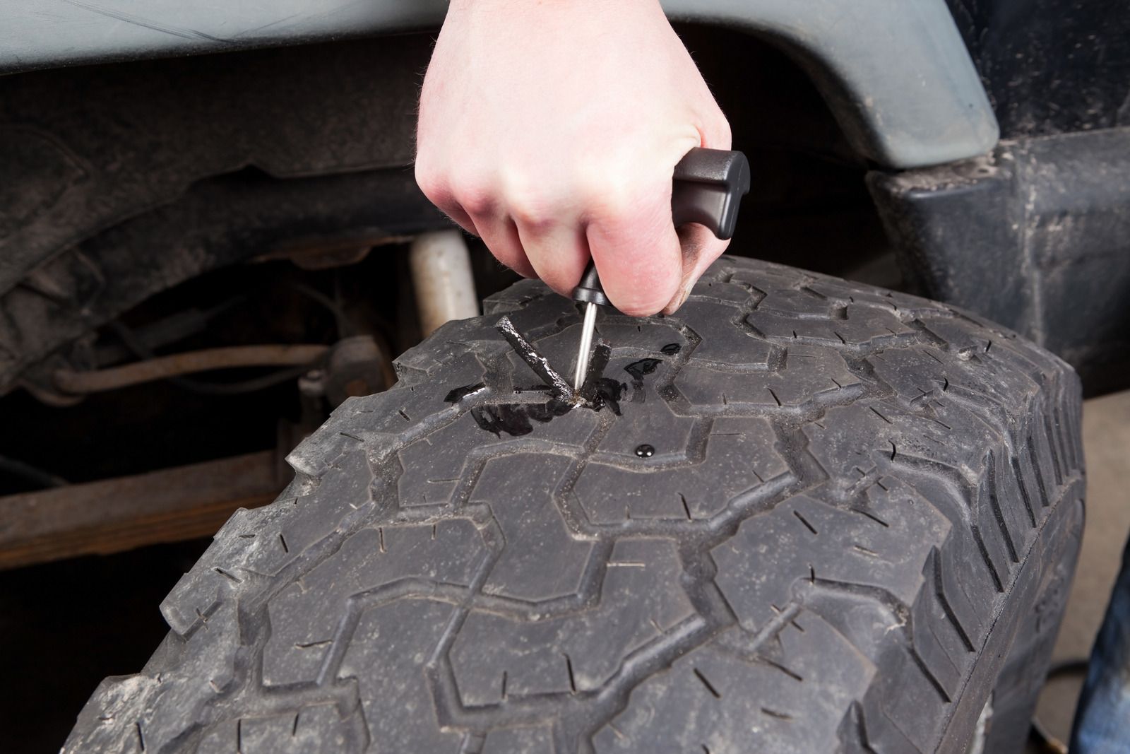 A person is fixing a tire with a screwdriver