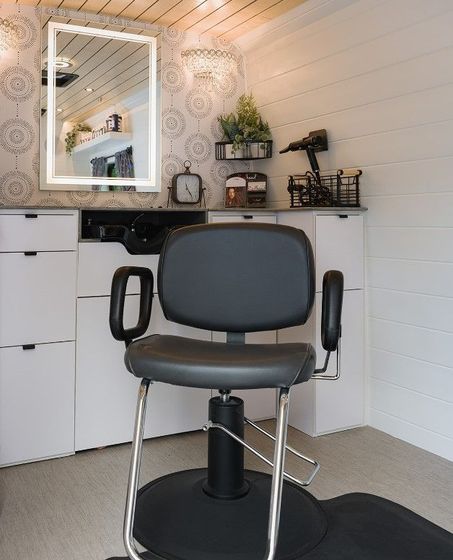 Photo showing a chair, mirror and hairstyling tools inside a mobile hair salon.