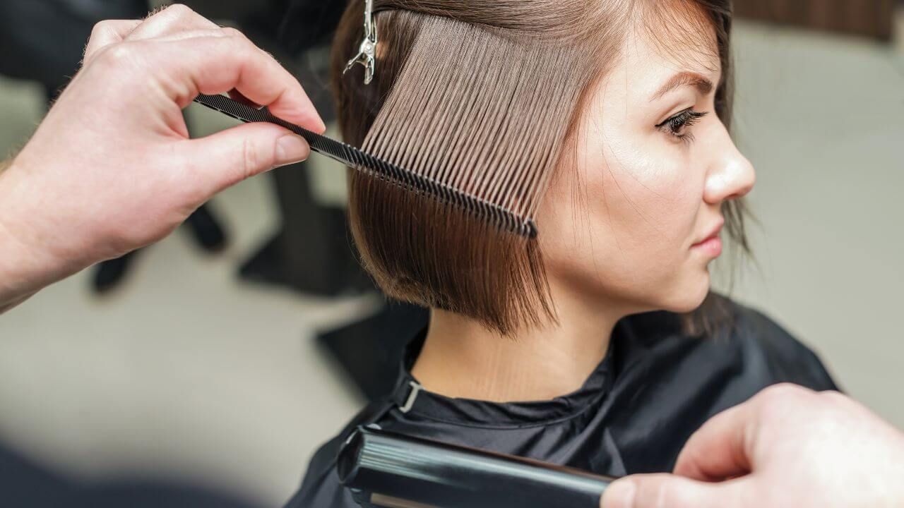 A woman sitting in a chair while a hairdresser cuts her hair.