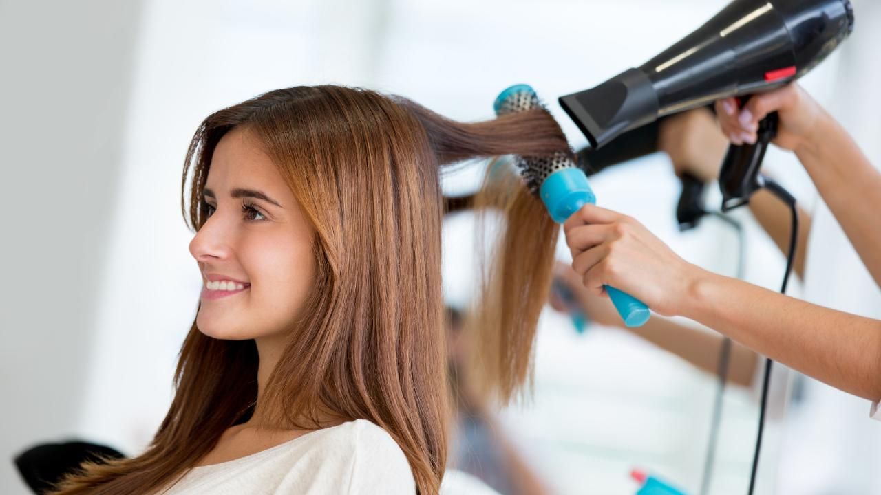 A woman receives a blow-dry from a stylist.