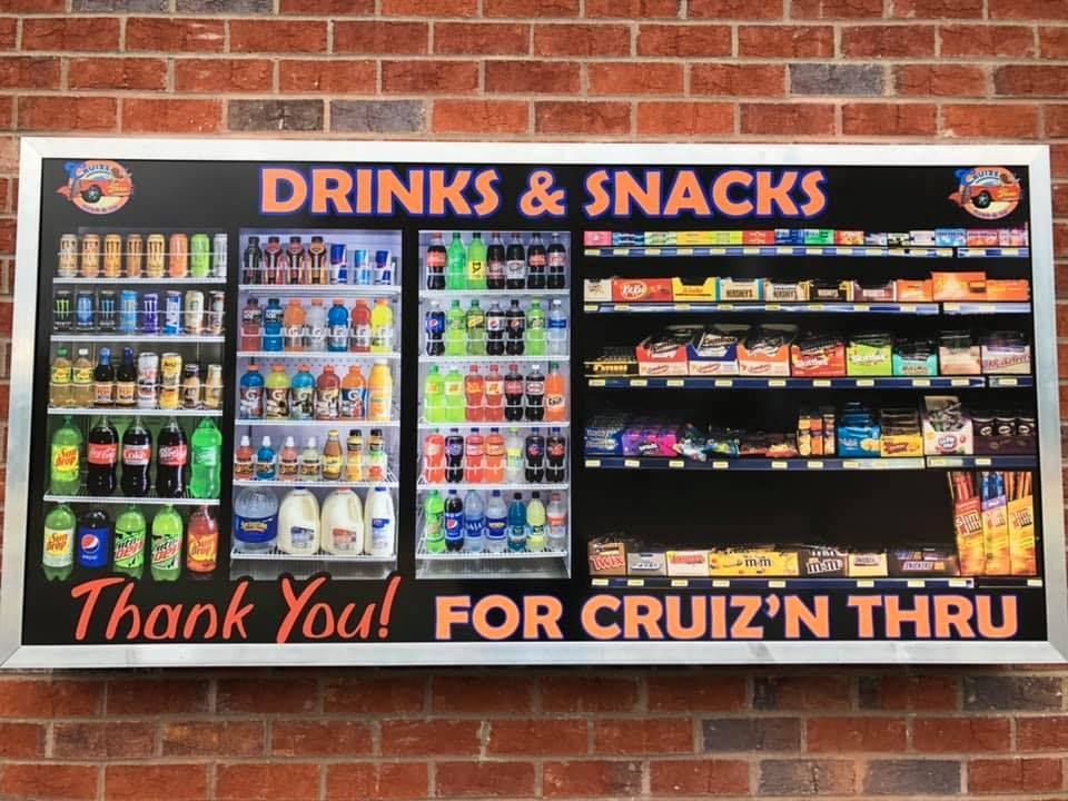 Sign for Cruiz'n Thru with drinks and snacks displayed: sodas, water, juices, milk, candy, chips, and snacks.