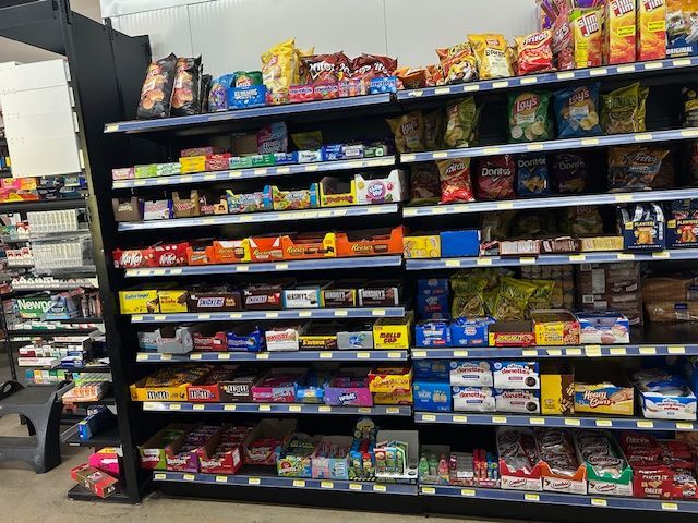 A retail store shelving unit packed with various snack foods, including bags of chips and boxes of candy and cookies.