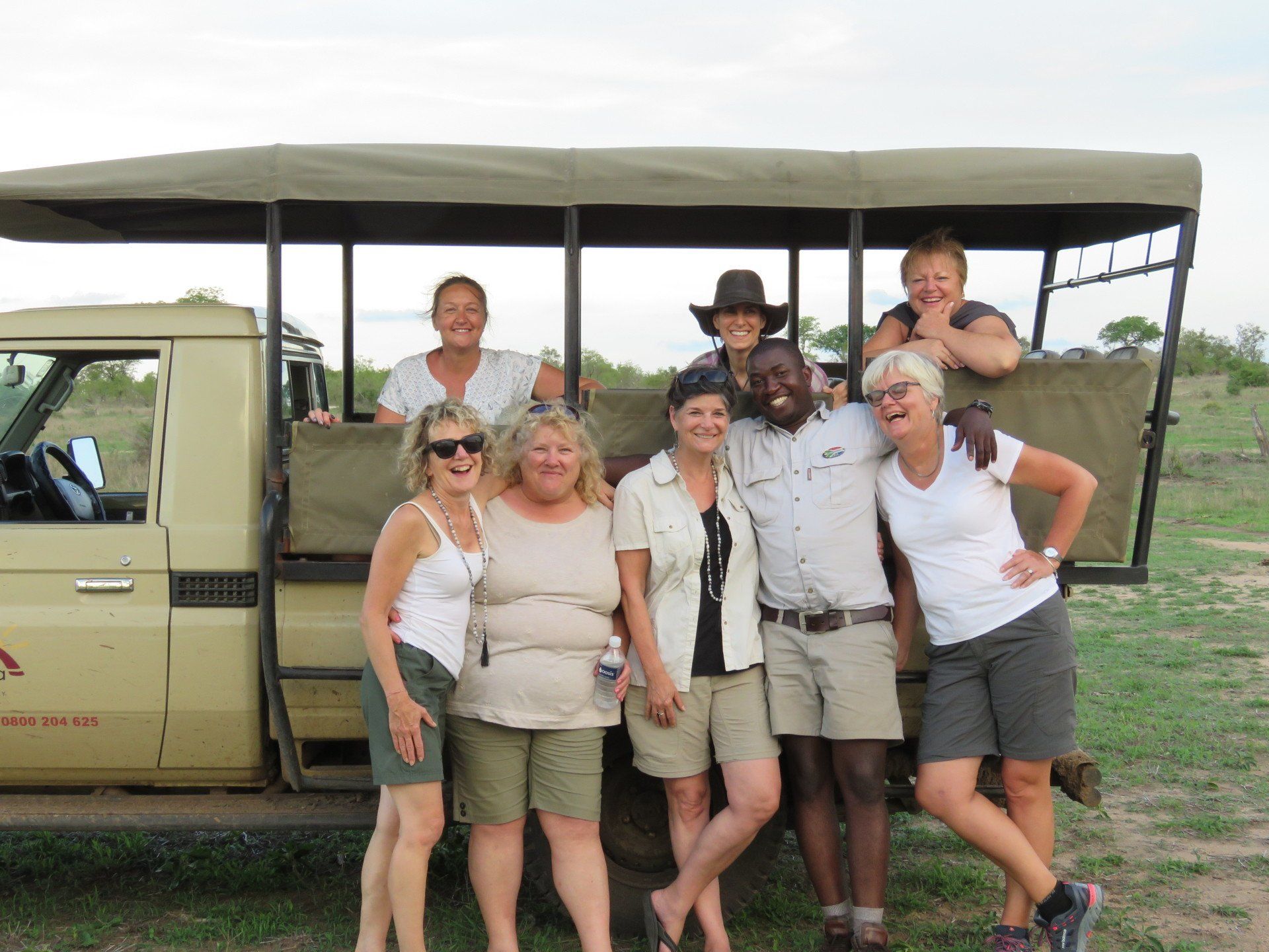 a group of people posing in front of a safari vehicle
