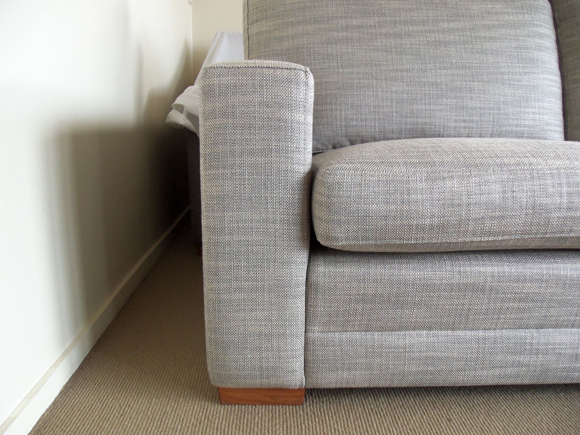 A couch is sitting in a corner of a room next to a wall.