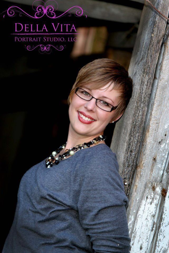 A woman wearing glasses and a necklace is smiling for the camera.