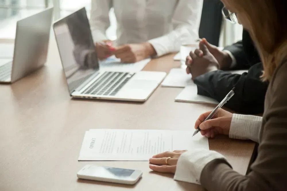 A Group of People Are Sitting at a Table With Laptops and Papers — Licensed Conveyancing Agent in Fannie Bay, NT