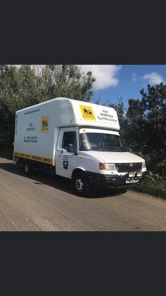 White box truck on a road, with company logos and a white cab, trees and blue sky in the background.