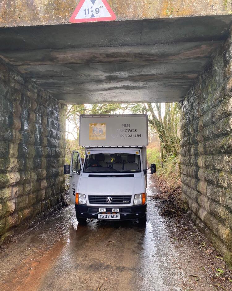 White van under a low bridge with a 11'9