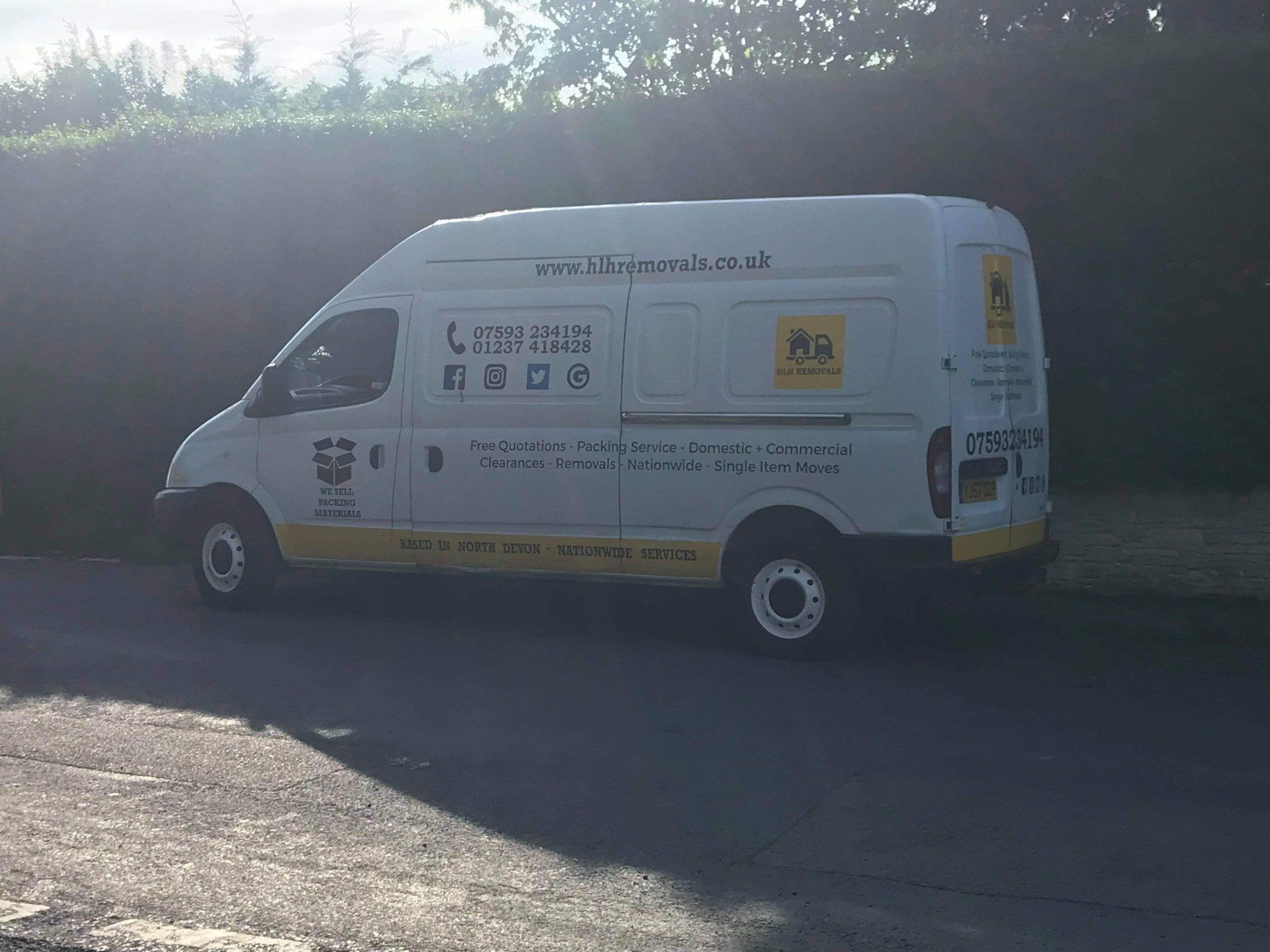 White van with yellow accents parked on a road, advertising a service.