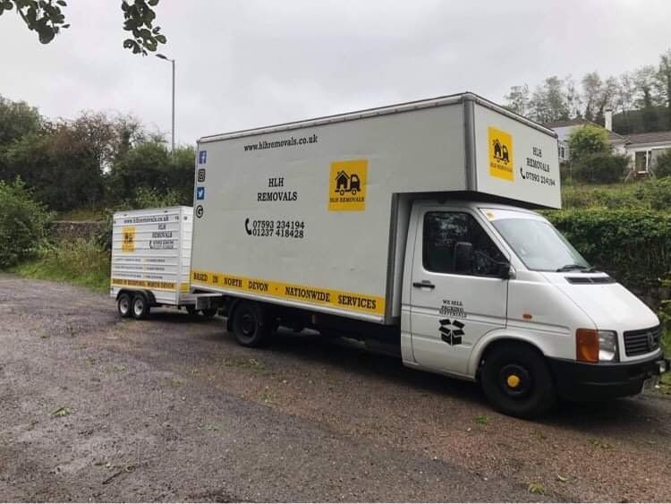 White moving truck with trailer on a rainy day.