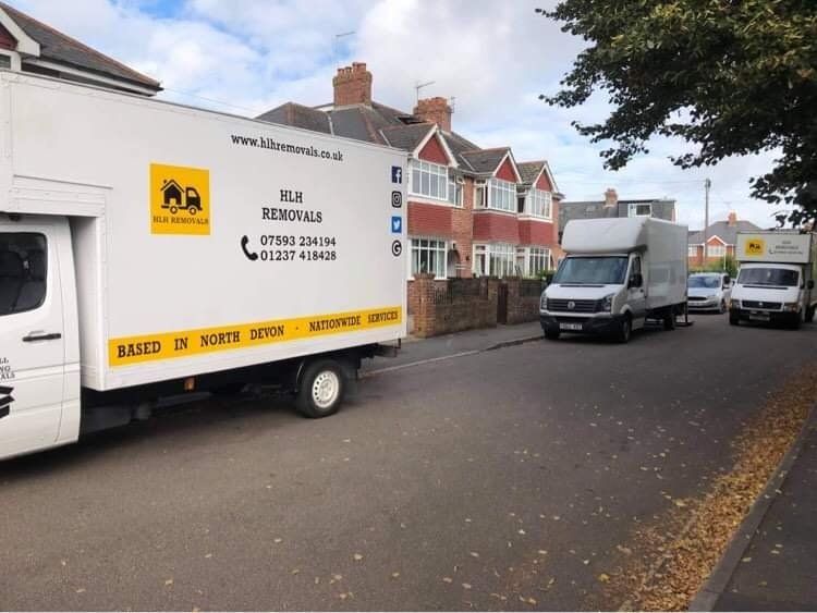 Moving vans on a residential street. One white van is branded with 