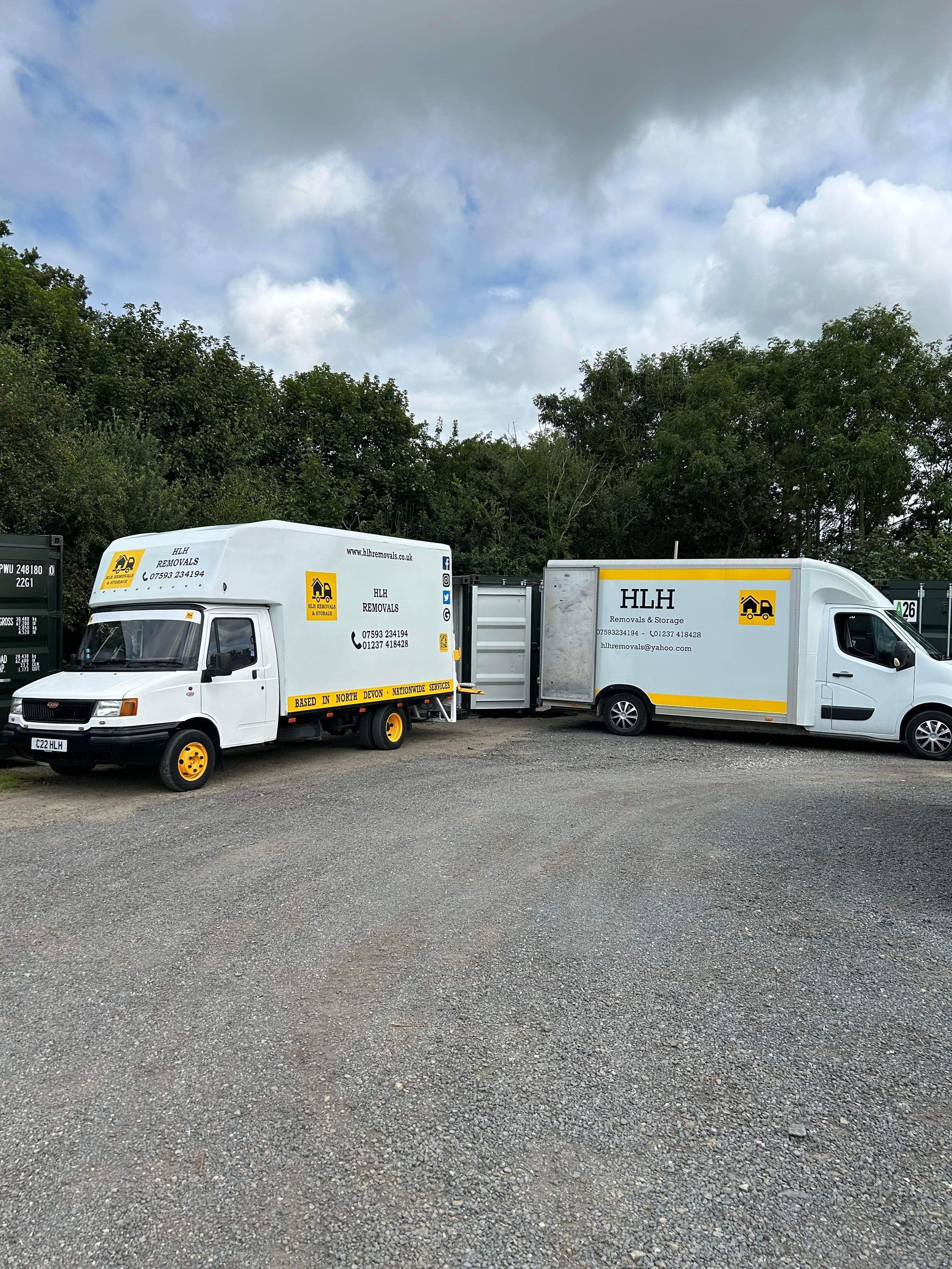 Two white service trucks with company logo parked on gravel.
