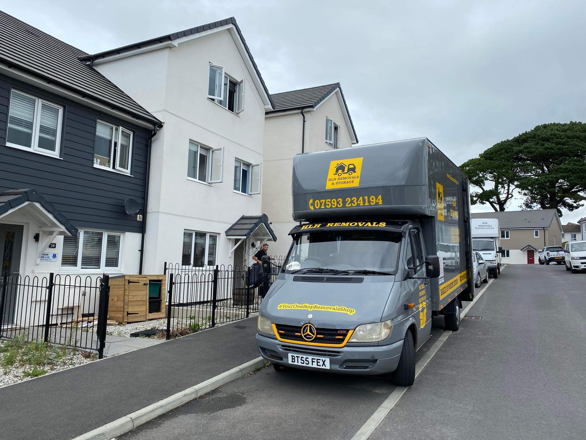Moving truck parked in front of residential townhouses on a cloudy day.