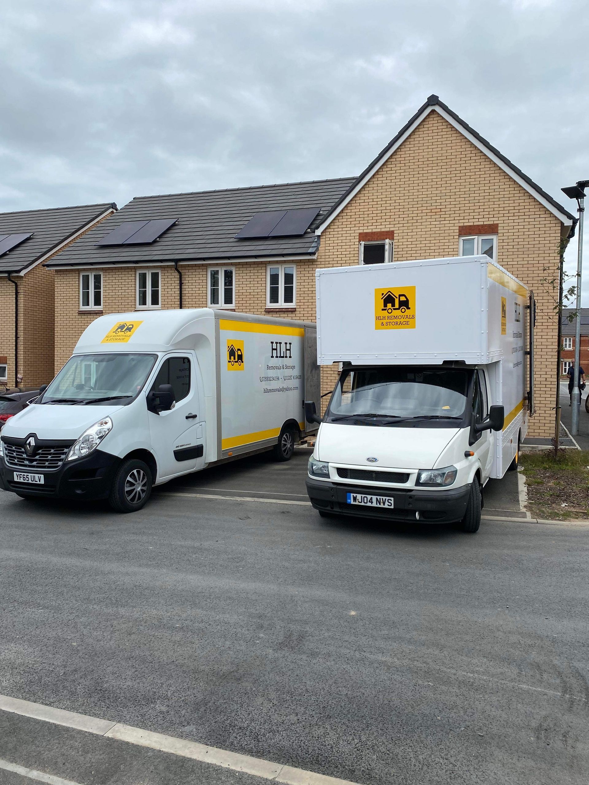 Two white moving vans parked in front of a residential building.