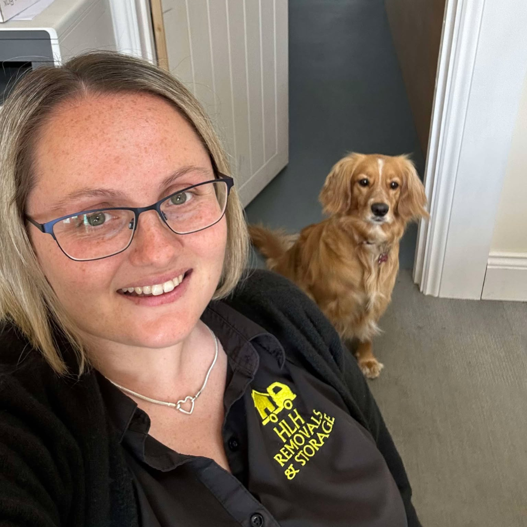Woman with glasses and dog in a doorway; the dog is looking forward.
