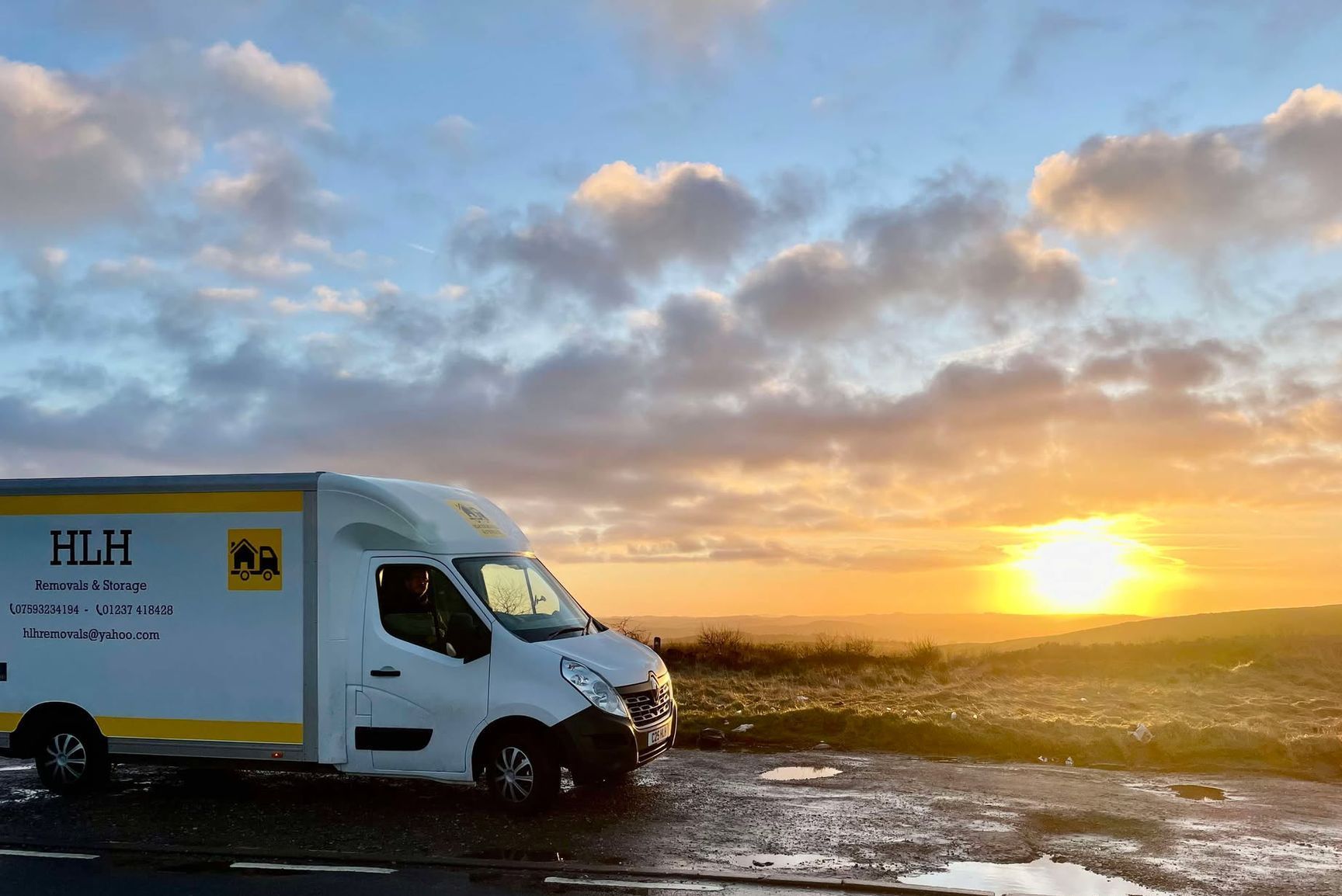 White delivery van parked at a sunrise, against a cloudy sky.