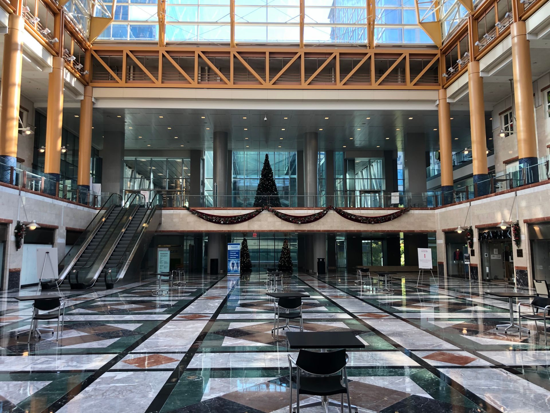 Grand indoor lobby with a tiled floor, glass walls, and a Christmas tree.