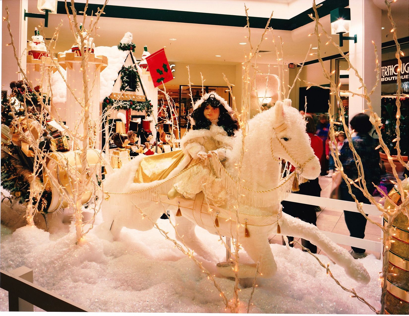 Girl on white horse in a holiday display. Snow-covered, with faux trees, and castle in background.