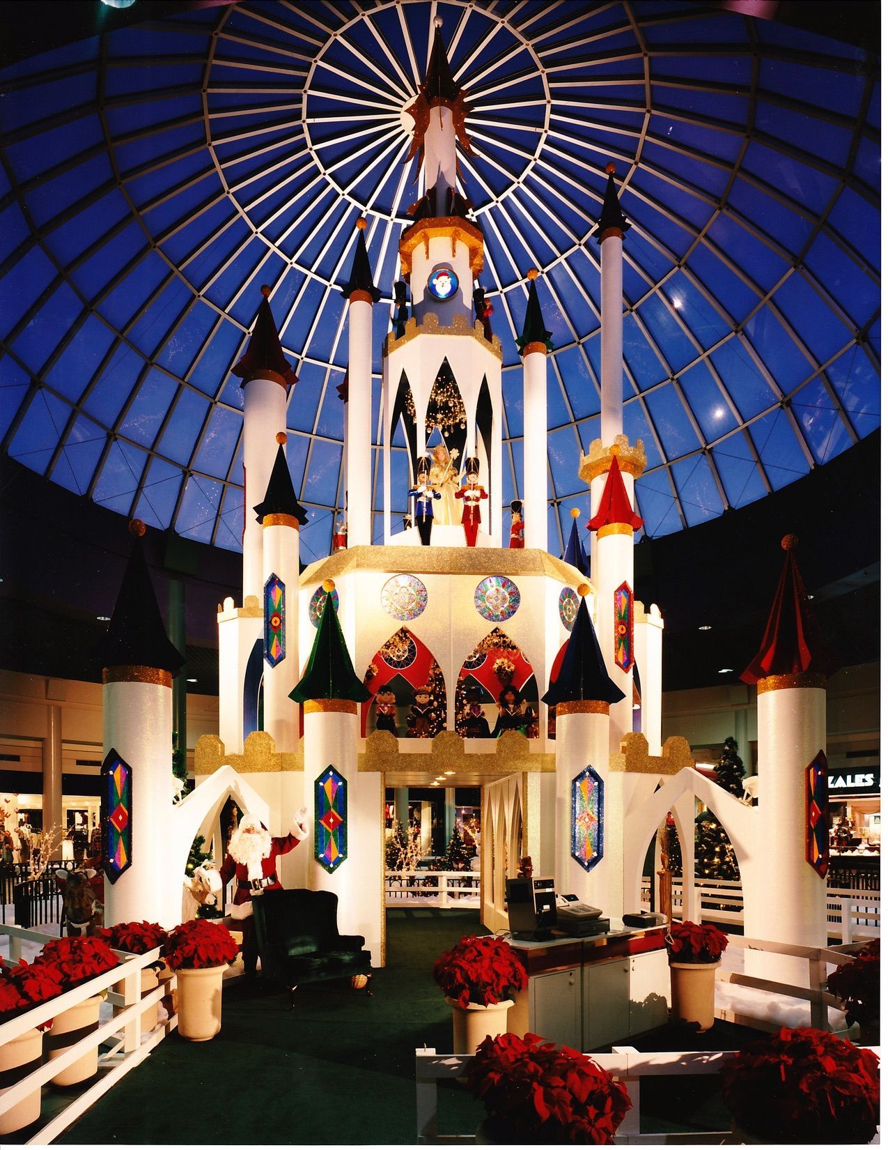 Christmas castle display inside a mall with a glass dome roof, with red and gold accents.