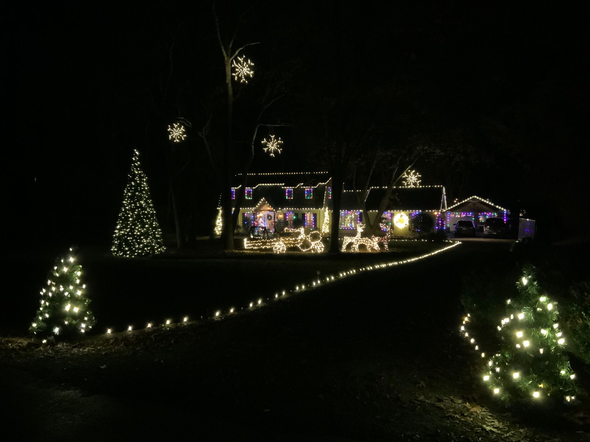 A house and yard illuminated with Christmas lights at night.