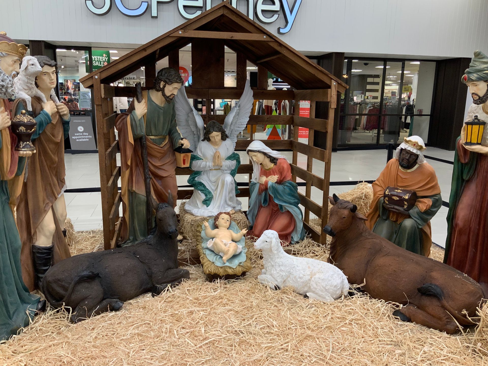 Nativity scene with figures in a wooden stable, including Mary, Joseph, baby Jesus, an angel, and the three wise men.