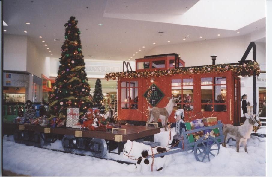Christmas display at a mall: train car, Christmas tree, reindeer, presents, and snow.
