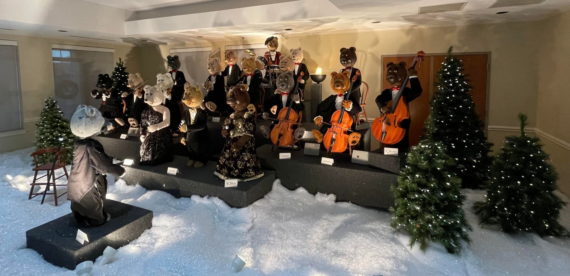 A festive display of bear musicians with Christmas trees in a snowy setting.