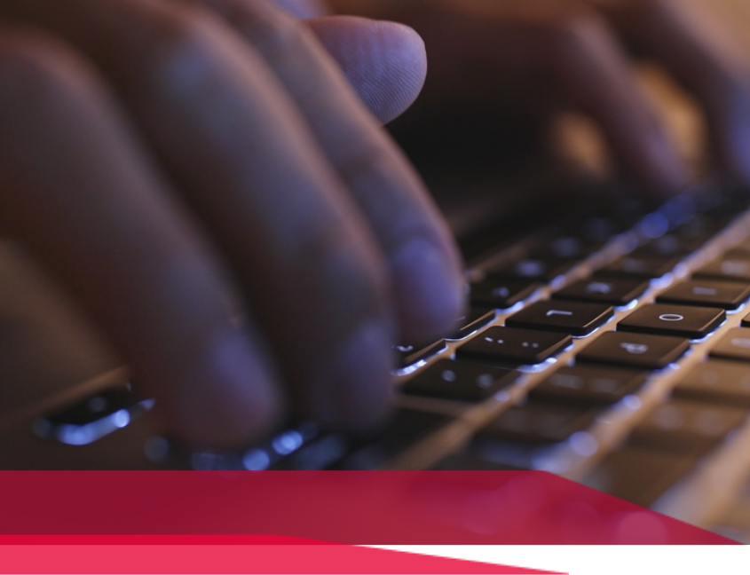 Hands typing on a laptop keyboard; close-up with a red graphic at the bottom.