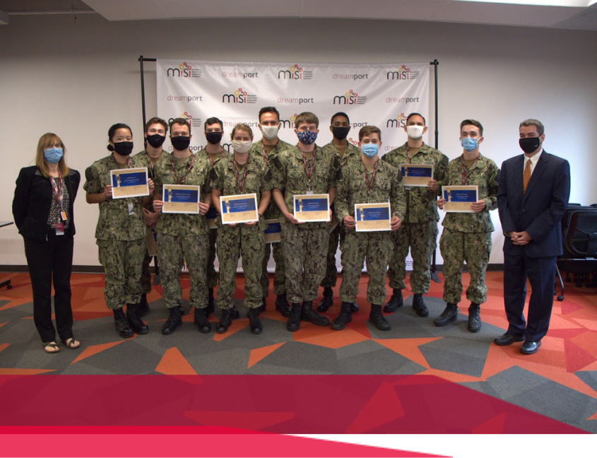 Group of naval personnel and two people in formal attire pose for a photo, holding certificates.