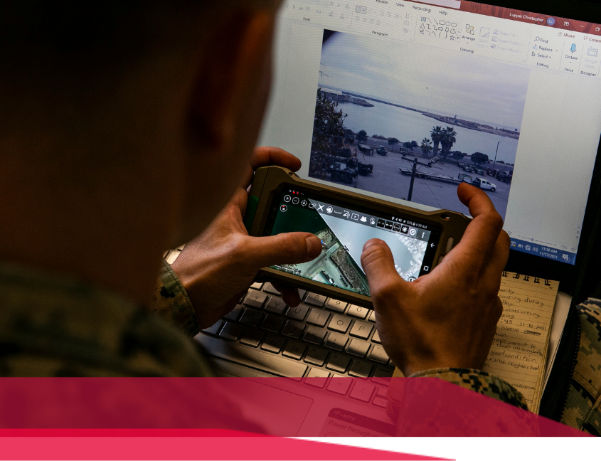 Person using a tablet and laptop, examining images of a waterfront location.