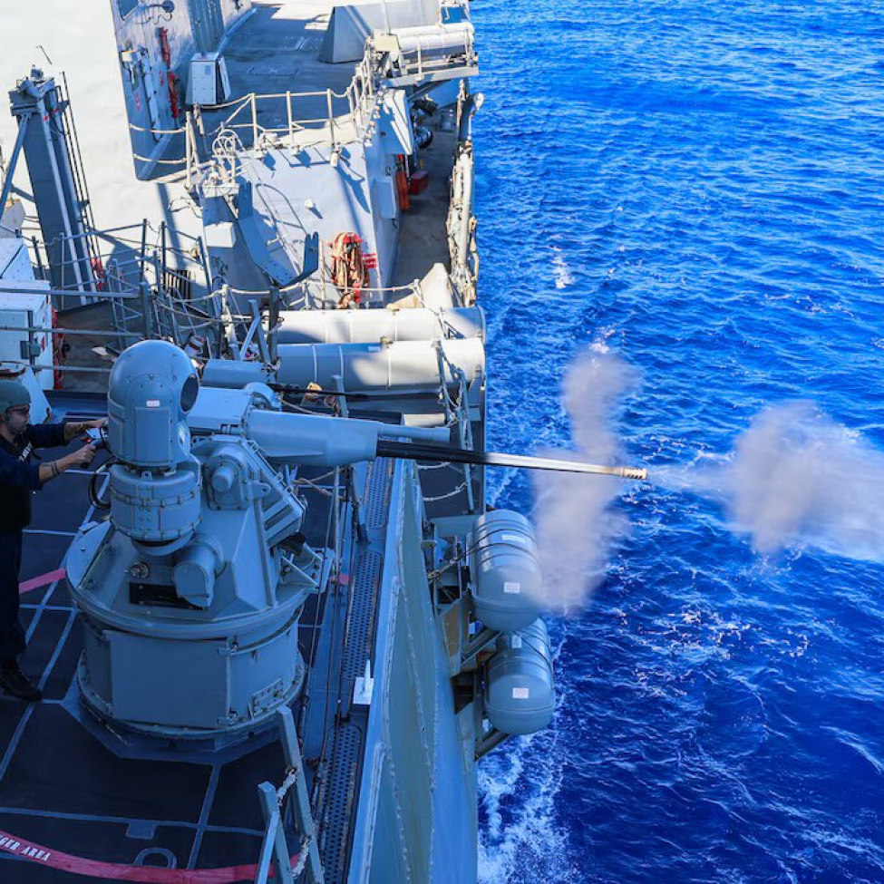 A military ship is firing a cannon into the ocean