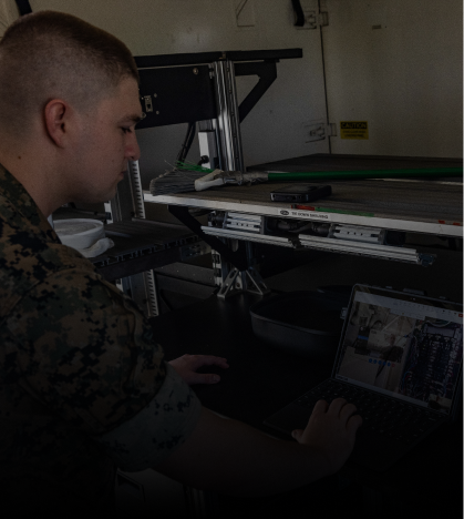 A man in a camouflage uniform is typing on a laptop